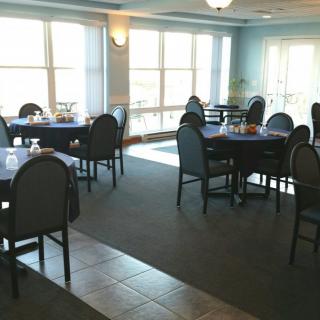 A cozy dining area with neatly arranged tables and chairs, illuminated by large windows.