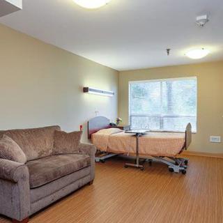 A clean and well-lit hospital room featuring a patient bed and a sofa.