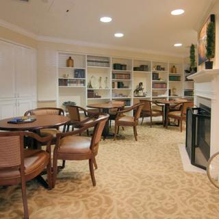 A cozy lounge area with tables, chairs, a fireplace, and bookshelves.