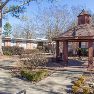 A sunny outdoor scene featuring a garden with a gazebo and pathways.