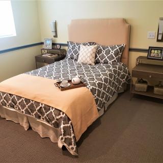 A cozy bedroom with a neatly made bed featuring patterned bedding and a headboard, flanked by wooden nightstands.