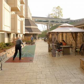 An outdoor courtyard with people sitting at tables and playing shuffleboard.