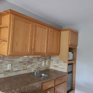 A kitchen area featuring wooden cabinets and a stone backsplash above a countertop with a sink.
