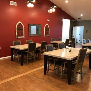 A cozy dining space featuring wooden tables and chairs with a warm red wall backdrop.