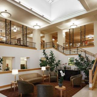 A spacious lobby with comfortable seating, decorative plants, and a grand staircase.
