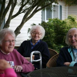 A group of elderly people sitting together outdoors, enjoying each other's company.