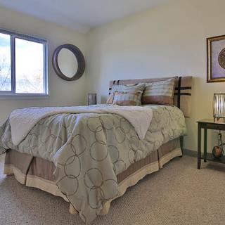 A cozy bedroom with a neatly made bed, a window, and decorative elements.