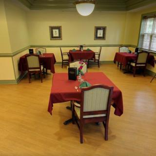 An empty dining room with tables covered in red tablecloths.