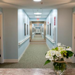 A well-lit hallway with a floral arrangement on a table in the foreground.