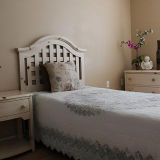 A minimalist bedroom featuring a single bed with floral decor and matching furniture.