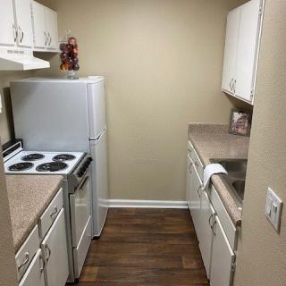A compact apartment kitchen with white cabinets and an electric stove.