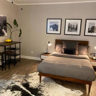 A modern bedroom with elegant decor and artwork, featuring a cozy bed, stylish furniture, and a patterned rug.
