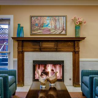 A cozy living room with a fireplace, surrounded by comfortable seating and adorned with artwork and decor.