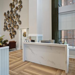 A modern reception area featuring a sleek desk, art installation, and wooden flooring.