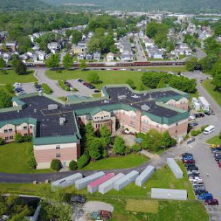 An aerial view of a residential building surrounded by greenery and a local town.
