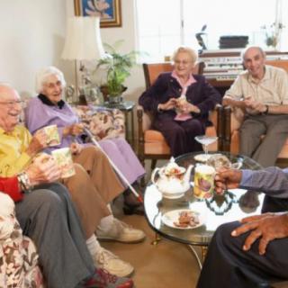 A group of seniors socializing and enjoying drinks in a living room setting.