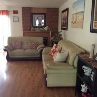 A cozy living room with comfortable sofas, artwork on the walls, and a wooden floor.
