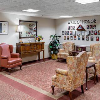 A cozy lobby area with armchairs and a 'Wall of Honor' featuring photographs.