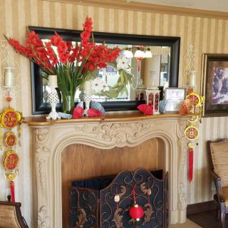 A decorated fireplace with a mirror, flowers, and traditional ornaments.