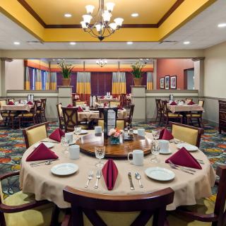 An elegant restaurant dining room with well-arranged table settings and a chandelier overhead.