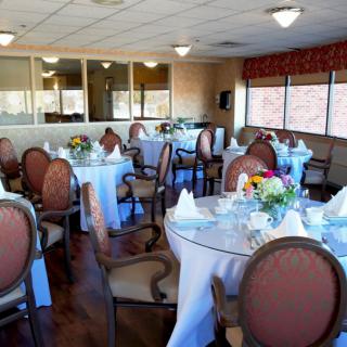 A formal restaurant dining room with elegantly set tables and floral centerpieces.