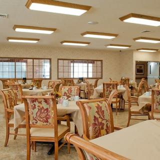 A spacious dining area with neatly arranged tables and chairs, illuminated by overhead lighting.