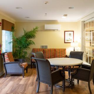 A cozy indoor lounge with a round table and chairs, complemented by a lush green plant and warm lighting.