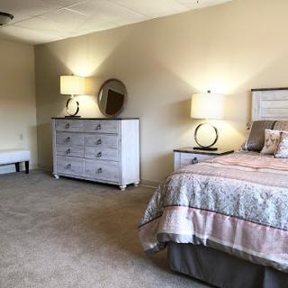 A cozy and elegantly designed bedroom featuring a comfortable bed, stylish dresser, and soft lighting.