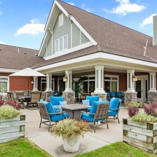 A cozy patio with blue chairs, set against a charming house under a clear sky.
