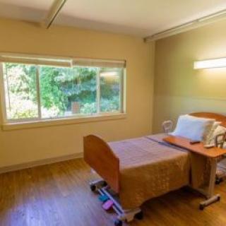 A minimalist hospital room with a single bed and a large window allowing natural light to fill the space.
