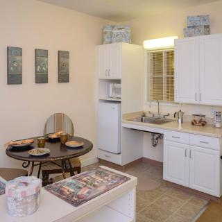 A cozy kitchen and dining area with modern white cabinets and a small round table.