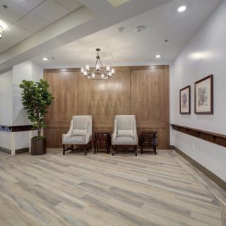 A stylish lobby area with two chairs, a chandelier, and wooden paneling.
