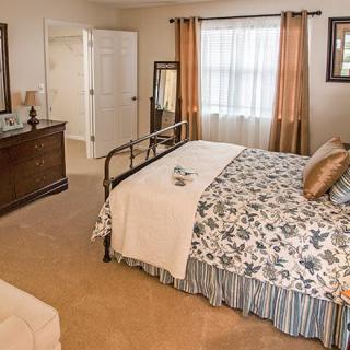 A cozy bedroom with a neatly made bed, dresser, and window.