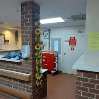 A hospital nurse station with sunflower decorations on a brick pillar and medical equipment nearby.