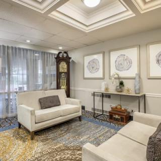 A cozy living room featuring elegant decor with sofas, a grandfather clock, and framed artwork on the walls.