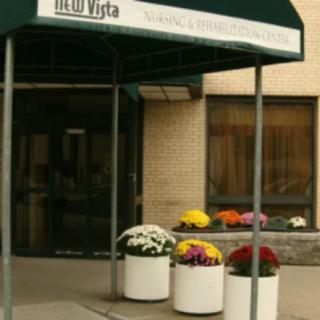 An entrance to a building with an awning and potted flowers.
