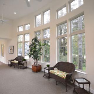 A well-lit waiting area with large windows, benches, and an indoor plant.