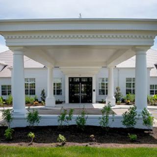 A grand building entrance featuring large columns and neatly arranged landscaping.