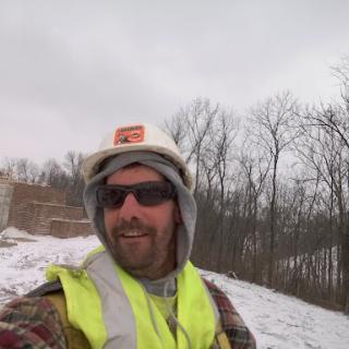 A construction worker taking a selfie on a snowy day.