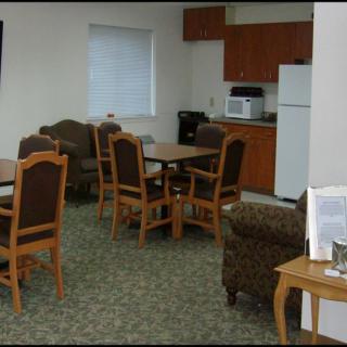A small dining area with tables and chairs, adjacent to a kitchen equipped with appliances.