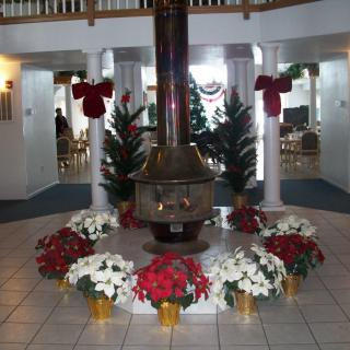 A festively decorated interior with a central fireplace surrounded by poinsettias and holiday wreaths.