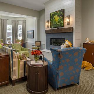 A cozy living room with stylish furniture and a fireplace, adorned with decorative elements.
