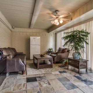 A cozy living room with comfortable seating, a ceiling fan, and ample natural light.