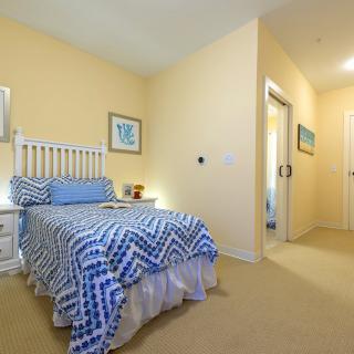 A cozy bedroom featuring a single bed with blue patterned bedding, complemented by a small nightstand and wall decor.