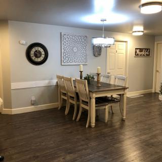 A well-lit dining room featuring a wooden table and chairs, with decorative wall art and hardwood flooring.