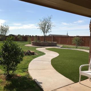 A serene view of a landscaped backyard with a winding pathway and lush greenery.