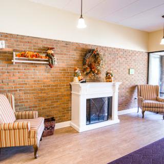 A cozy waiting area featuring a fireplace and comfortable seating against a warm brick wall.