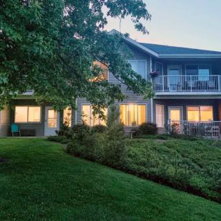 A two-story house with illuminated windows, surrounded by a well-maintained garden and lawn during the evening.