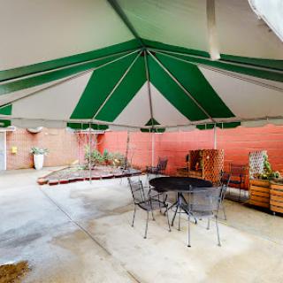 A cozy outdoor dining area under a green and white striped tent.