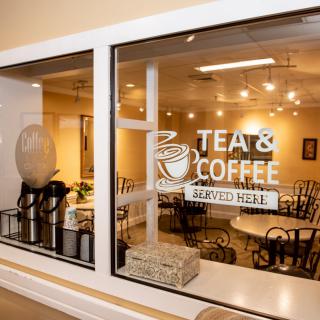 A glass window adorned with a 'Tea & Coffee' sign reveals a cozy cafe interior.
